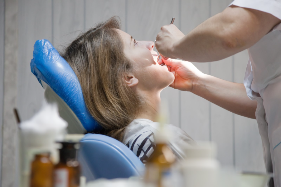 Woman in a dental chair undergoing treatment as a dentist works inside her mouth.